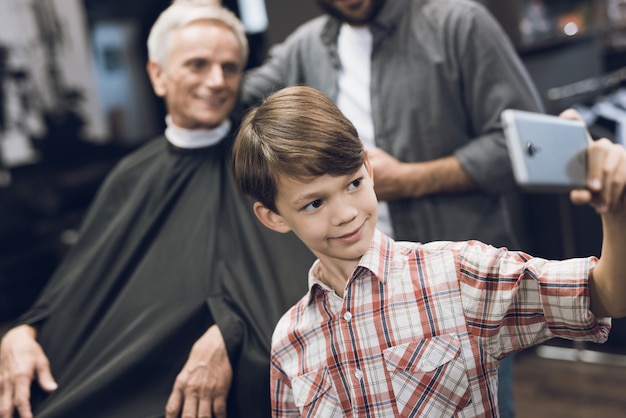 The boy makes selfie on a smartphone with two older men. Premium Photo