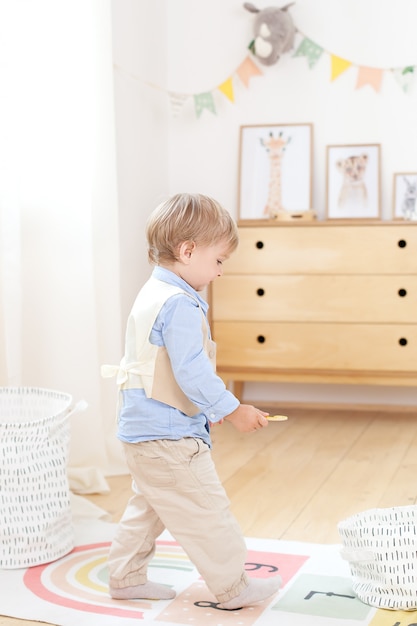 部屋でおもちゃで遊ぶ少年 スカンジナビアの環境に優しい子供部屋の装飾 幼稚園で遊んでいる少年の肖像画 子供部屋とインテリアデザイン 少年は家にいます 小さな男の子 プレミアム写真