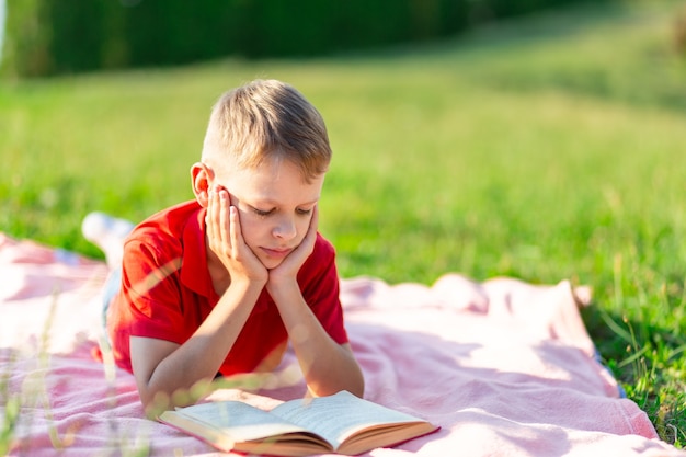 Premium Photo | Boy reading a book in the park against a background of ...