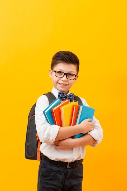 Free Photo | Boy with backpack holding stack of books