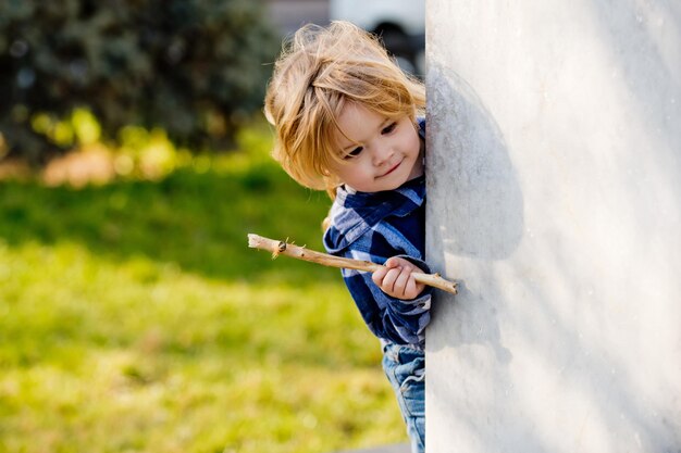 premium-photo-boy-with-blond-hair-with-stick-smile-at-wall-corner