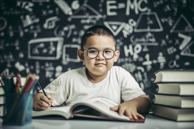 A boy with glasses man writing in the classroom Free Photo