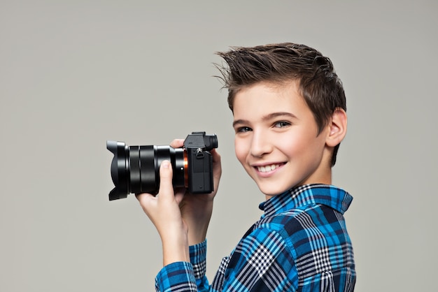 写真を撮る写真カメラを持つ少年 手にデジタルカメラを持つ白人の少年の肖像画 無料の写真