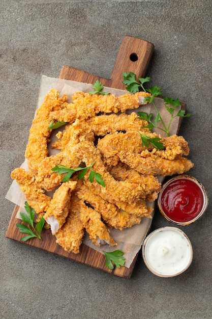 Premium Photo | Breaded chicken strips with two kinds of sauces.