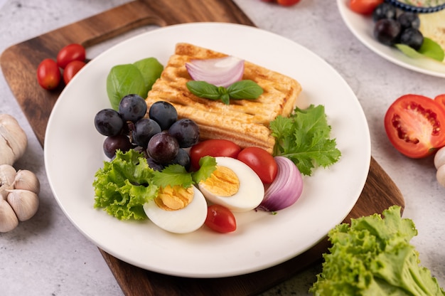 朝食は パン ゆで卵 黒ブドウのサラダドレッシング トマト スライスした 玉ねぎ で構成されています 無料の写真