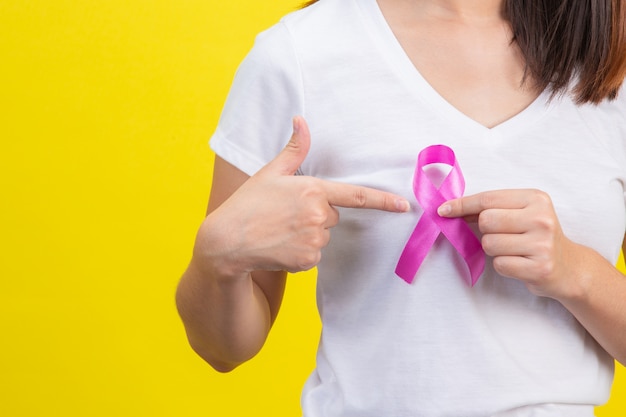 Breast cancer , a woman in a white t-shirt with a satin pink ribbon on her chest, a symbol for breast cancer awareness Free Photo