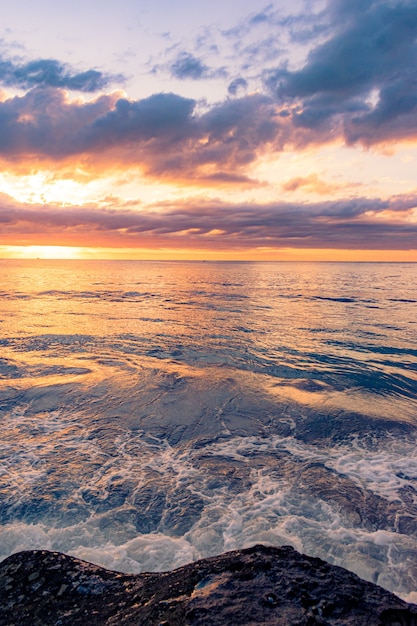 美しい夕日を背景に岩のビーチの息を呑むような風景 無料の写真