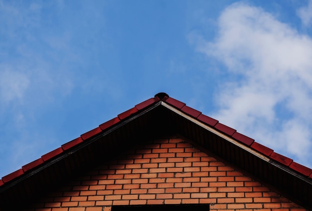 青い空を背景にレンガ造りの家 民家の屋根 プレミアム写真