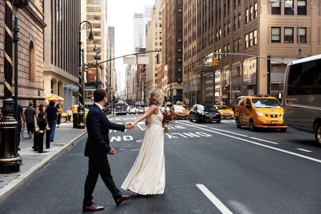 Free Photo Bride Holds Groom S Hand Walking Across The Street In New York