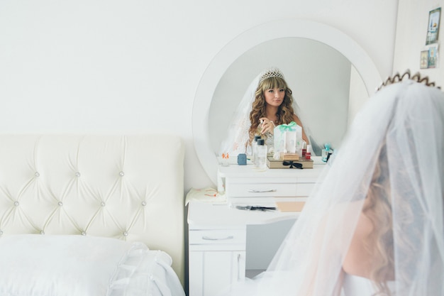 The Bride Looks In The Mirror And Uses Perfume In The White