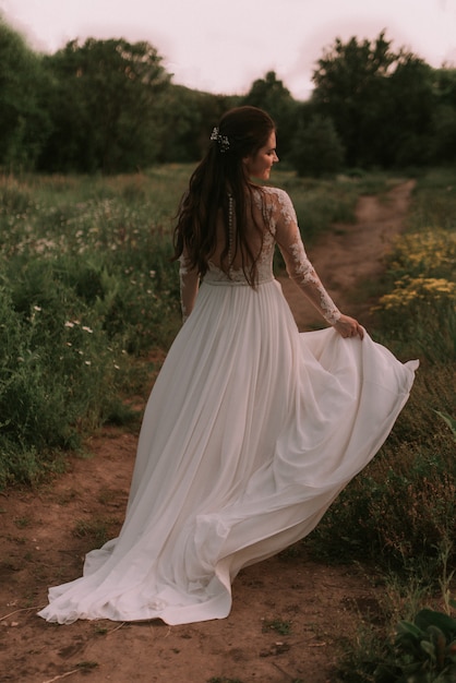 Premium Photo | Bride running through the park holding dress