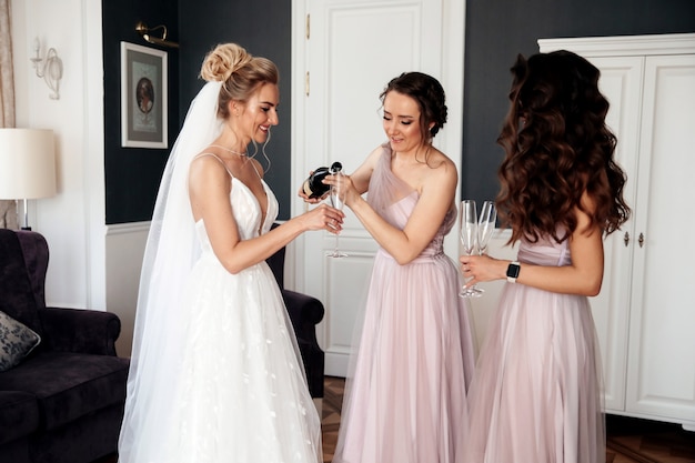 花嫁の女友達が花嫁と別の女性にシャンパンを注いでいる 無料の写真