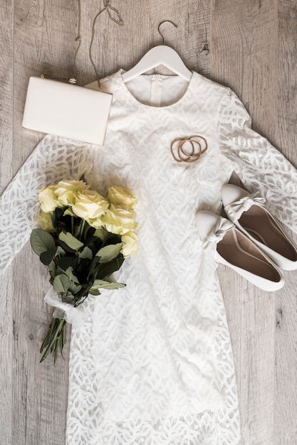 靴クラッチ付きの花嫁のウェディングドレス Hairbandsとバラの花束は 木の背景に白いリボンで結ば 無料の写真