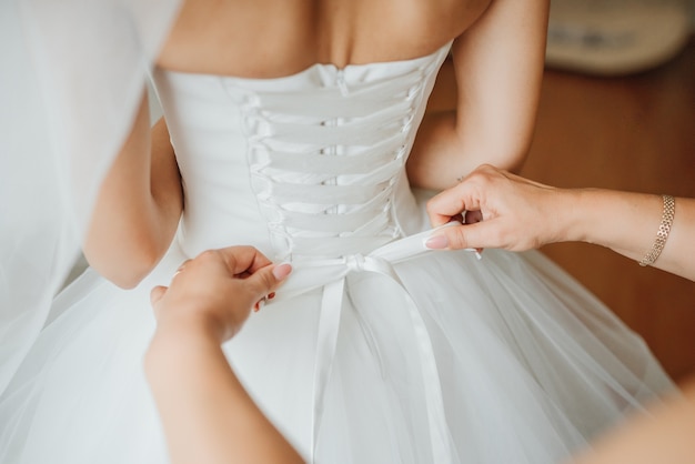 Bridesmaid making bow-knot on the back of bride's wedding dress | Photo: Freepik