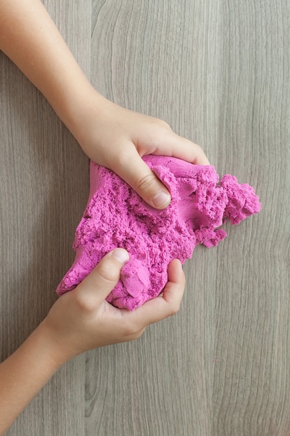 Premium Photo | Bright pink kinetic sand in the hands of a child