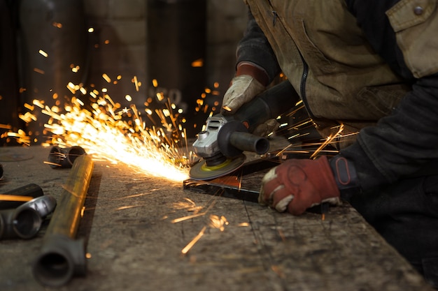 Premium Photo | Bright sparks flying when the worker grinds the metal ...