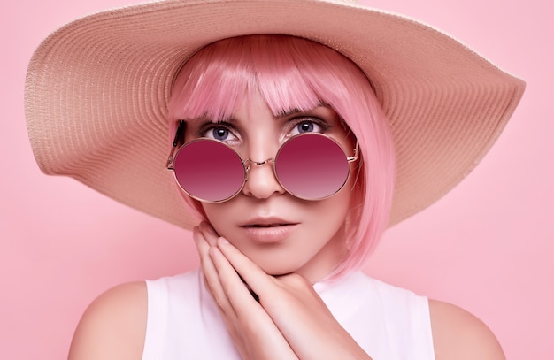 ピンクの髪 サングラス カラフルなスタジオの編みこみの帽子を持つポジティブでゴージャスな女の子の明るい夏の肖像画 プレミアム写真