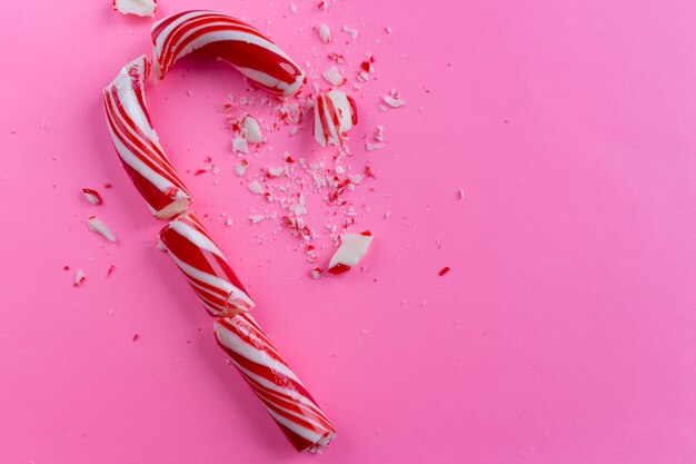 Premium Photo | Broken candy cane on pink background.