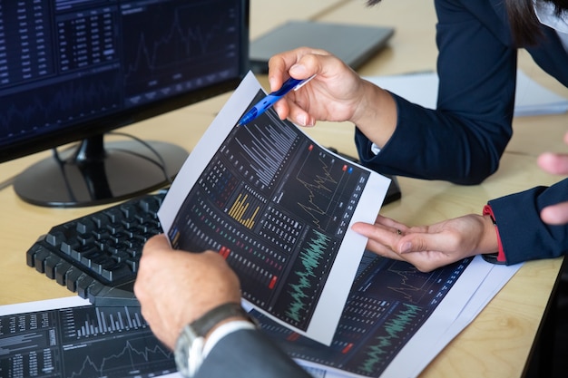 Brokers discussing trading strategy, holding papers with financial data, pointing pen at charts. cropped shot. broker job or stock market exchange concept Free Photo