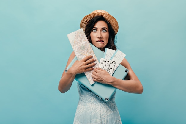 Free Photo Brunette Girl Feels Awkward And Poses With Suitcase Tickets On Blue Background Woman In Straw Hat With Map In Her Hands And In Blue Dress