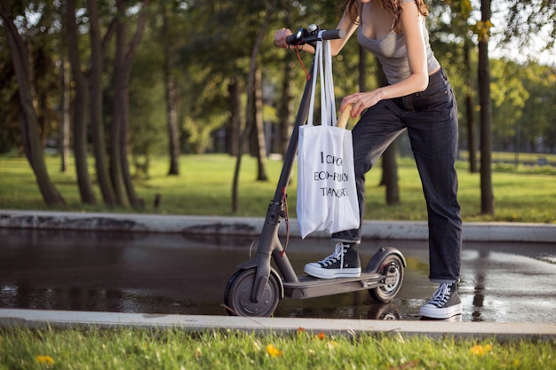 Premium Photo A Brunette Girl Is Standing Next To Electric Scooter In The Park And Pulls Out Of A Bag Bread