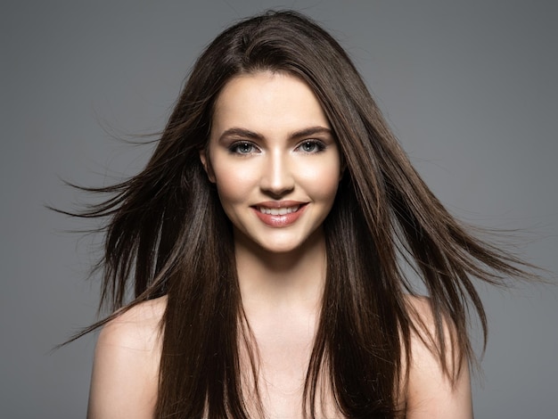 Brunette smiling woman with beauty long brown hair. fashion model with long straight hair. fashion model posing . pretty woman with long straight brown hair. Free Photo
