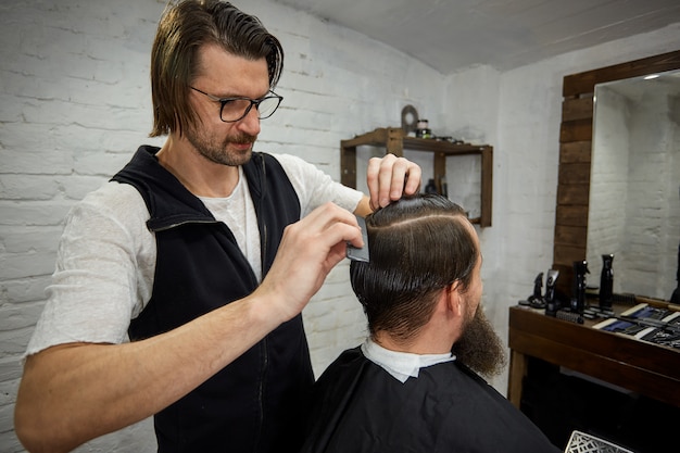 Premium Photo | Brutal guy in modern barber shop. hairdresser makes ...