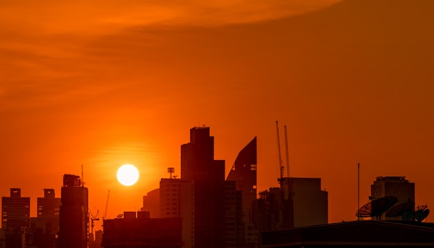 美しい夕焼け空と夕暮れ時にダウンタウンの建物 夜のマンションとアパートのシルエット 高層ビルの建物と建設クレーンの街並み プレミアム写真