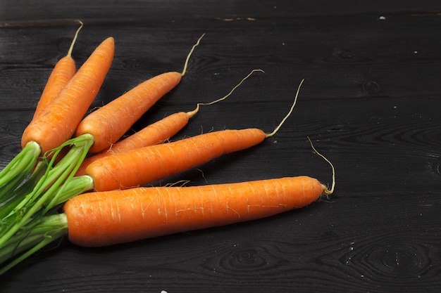 Bunch of fresh carrots with green leaves on wooden table Premium Photo