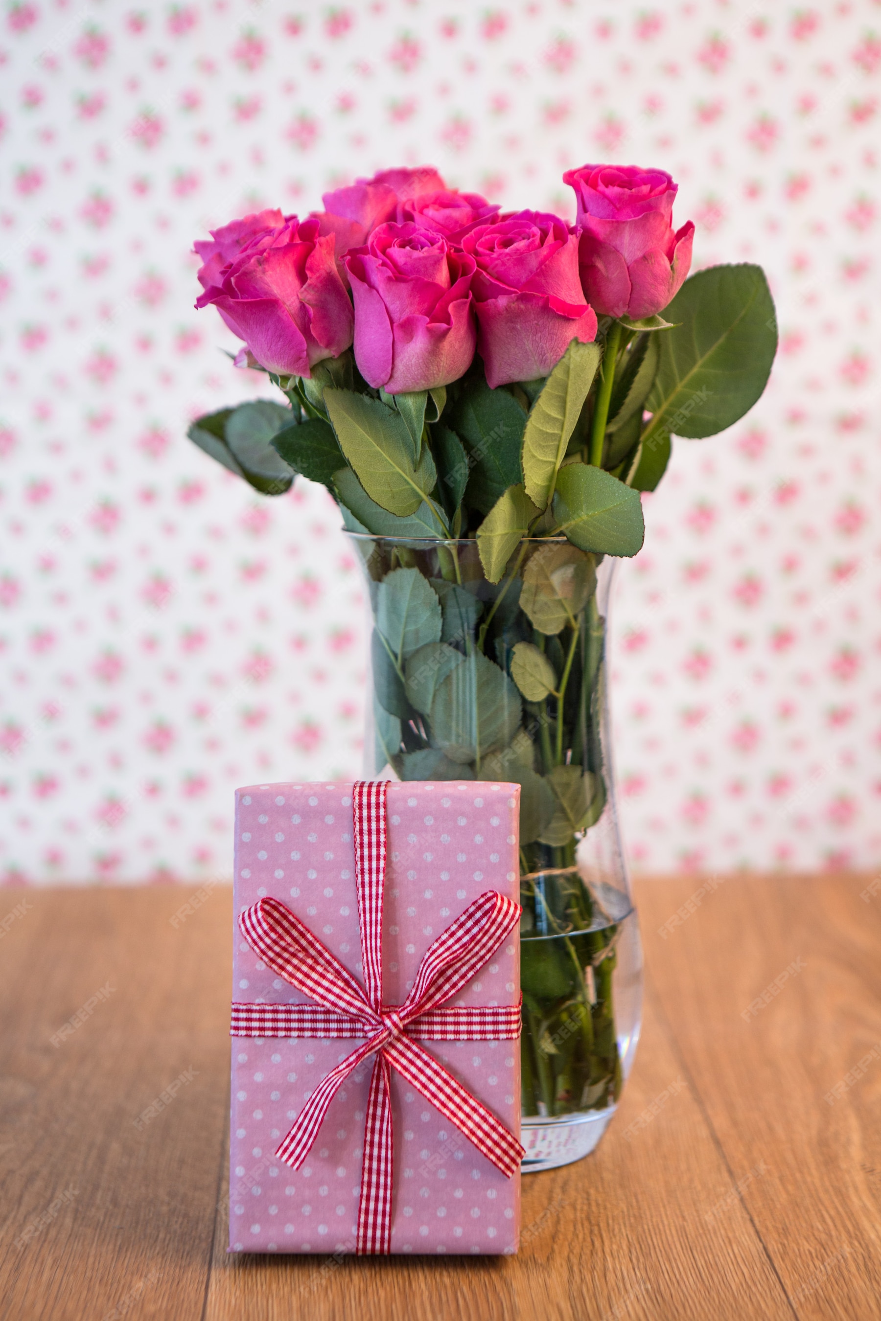 Premium Photo | Bunch of pink roses in vase with pink gift leaning ...