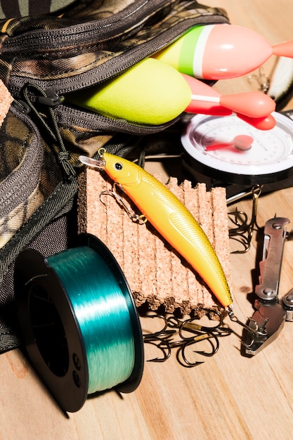 Buoy in bag; fishing lure and fishing reel on wooden desk Free Photo