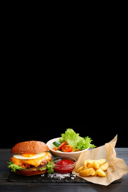 Premium Photo | Burger with egg with fries and ketchup sauce on wooden ...