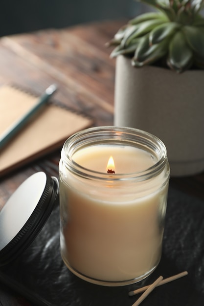 Premium Photo | Burning candle in glass jar, succulent and notebook on ...