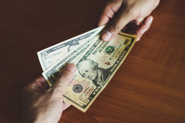 Business man give money bribe concept - person hands man giving money on wooden table background ...