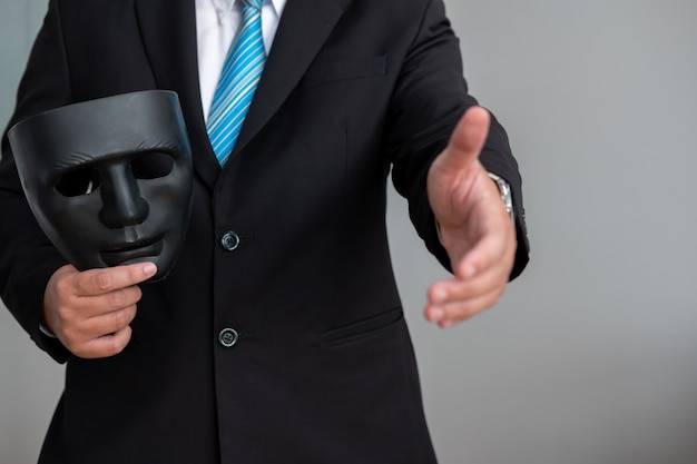 Business man with a black mask covering the insincerity of doing ...