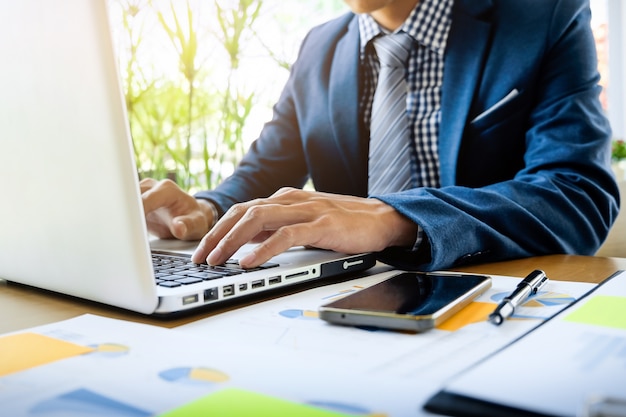 Business man working at office with laptop, tablet and graph data documents on his desk Free Photo Business man working at office with laptop, tablet and graph data documents on his desk Free Photo