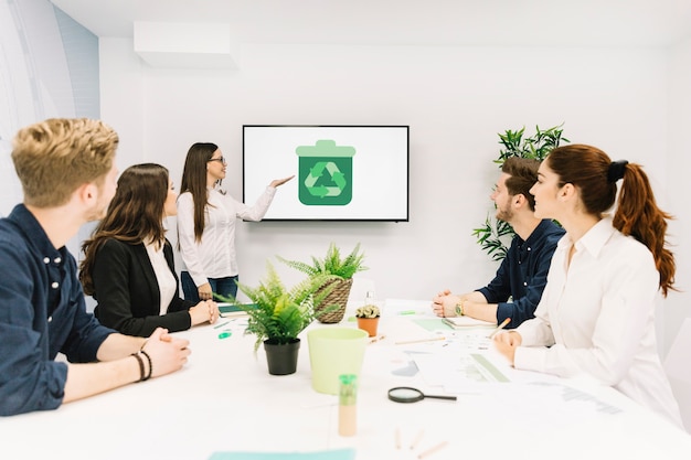 Business partners looking at female manager giving presentation with recycle icon on screen Free Photo Business partners looking at female manager giving presentation with recycle icon on screen Free Photo