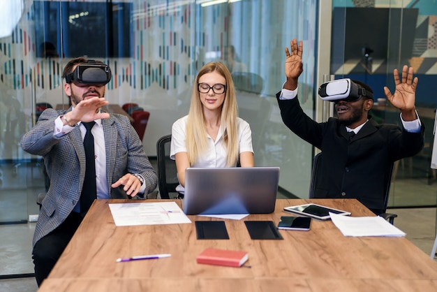 Business people using virtual reality goggles during meeting. team of developers testing virtual reality headset and discussing new ideas to improve the visual experience. Premium Photo