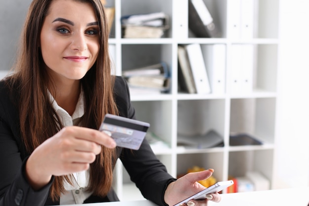 Business woman in the office holds a plastic credit debit card in her hand Premium Photo