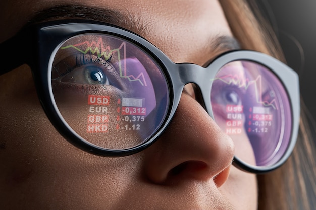  Business woman with glasses looks at stock market quotes and exchange rates during the financial cr