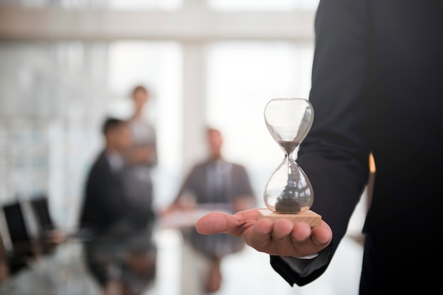 Businessman holding an hour glass, signifies the importance of being on time Free Photo