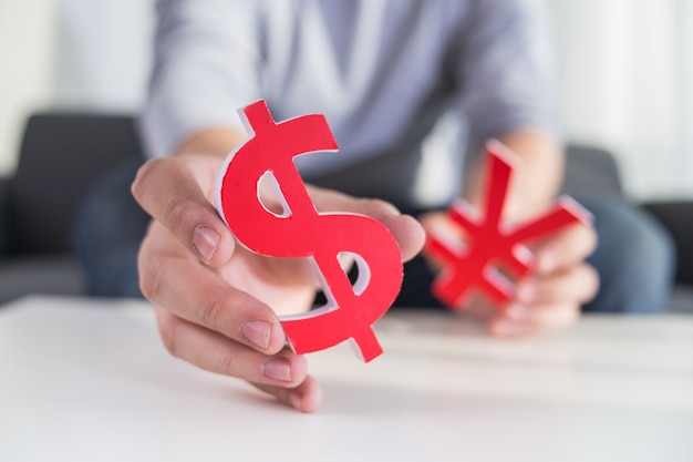 Businessman holding dollar sign and CNY sign Free Photo