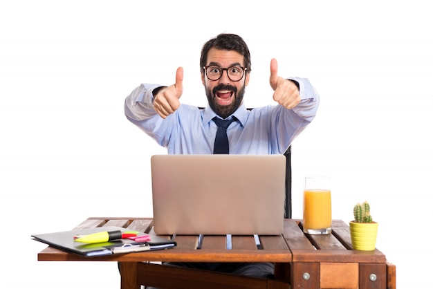 Businessman in his office with thumb up Free Photo