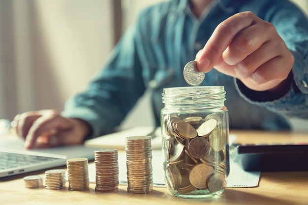 Premium Photo | Businessman puting coins into jug glass