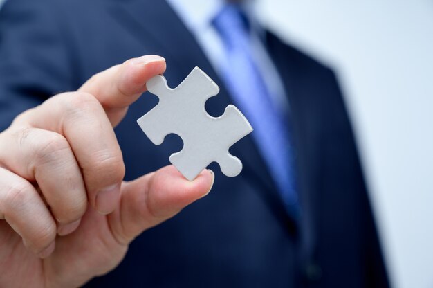 Premium Photo | Businessman showing a jigsaw puzzle piece