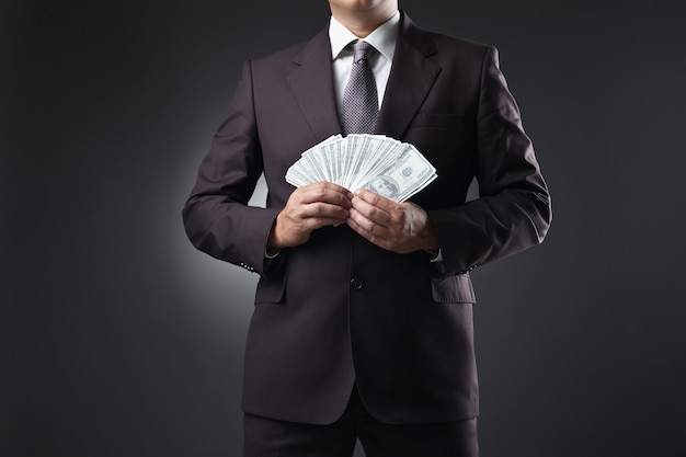 Premium Photo | Businessman in suit holding money in hands on dark ...