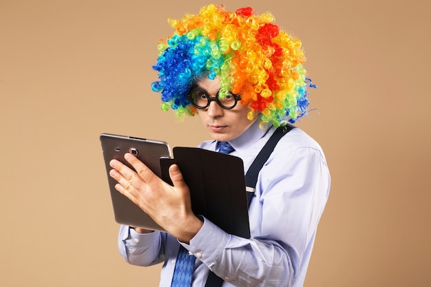 Premium | Businessman with tablet portrait of business man in clown wig using a tablet access the internet. business concept. multitasking