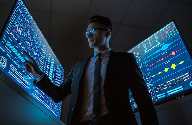 Premium Photo | The businessman working on the blue monitor in the dark lab