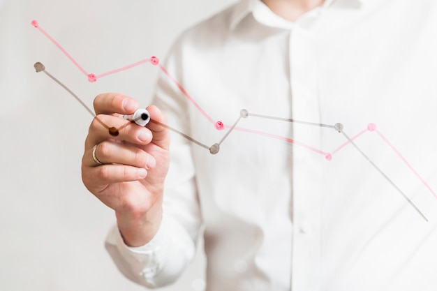 Businessperson's hand preparing graphs on glass board with marker Free Photo