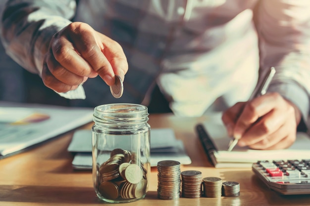 Businesswoman holding coins and putting in glass Premium Photo